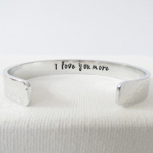 wide hammered texture aluminium cuff bracelet with the message 'I love you more' hand-stamped inside
