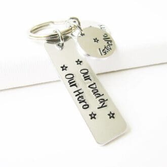 slim rectangular aluminium keyring with the eords 'our daddy, our hero' hand-stamped on it with personalised name tags attached