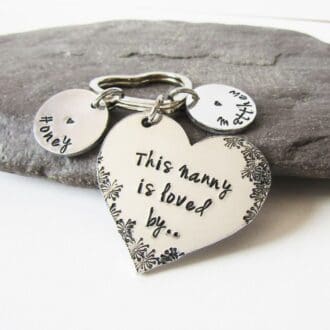 aluminium heart keyring hand-stamped with 'this Nanny is loved by' with flower detailing and personalised name tags
