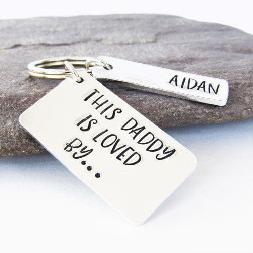 rectangular aluminium keyring hand-stamped with the words 'this daddy is loved by' with personalised name tags