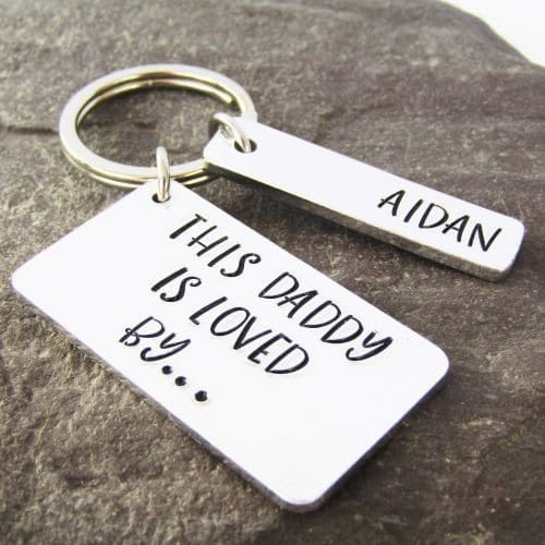 rectangular aluminium keyring hand-stamped with the words 'this daddy is loved by' with personalised name tags