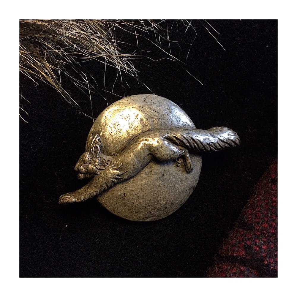 Pewter Red squirrel brooch showing a squirrel leaping across a round sun with a nut in its mouth. Designed, sculpted and handmade by sculptor Kirsty Armstrong