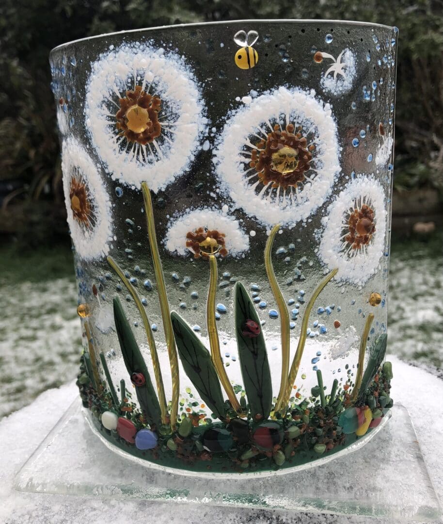 Fused glass dandelion heads and seed pods on a curved glass with a base