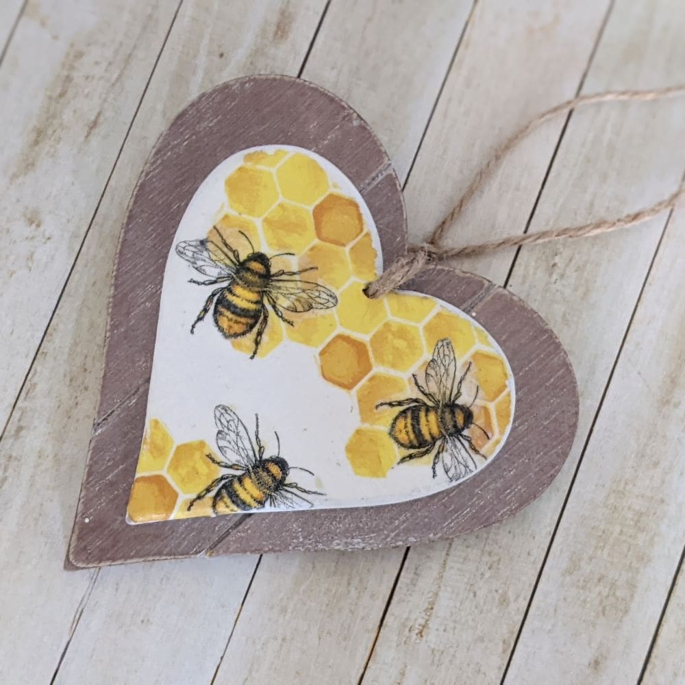 Two layer wooden hanging heart decoupaged with a bee and honeycomb design, finished with a natural twine hanger.