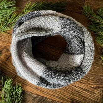 Infinity scarf, knitted in colour blocks of textured yarn in shades of grey