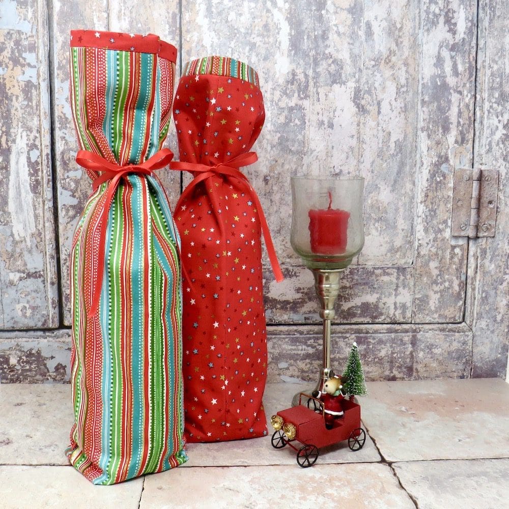 Fabric bottle gift bags in two designs, one red and green stripes and the other has stars on a red background.