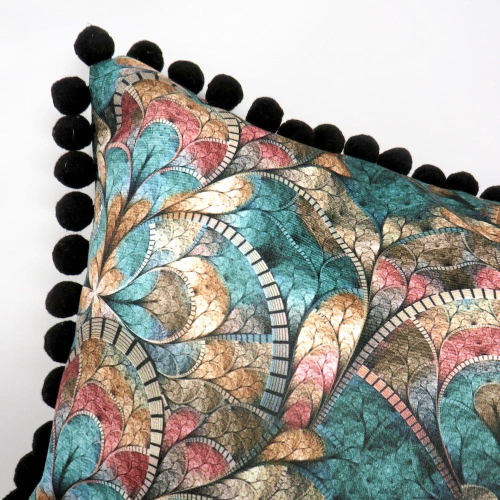 A beautiful green velvet print cushion with a black pom pom trim.