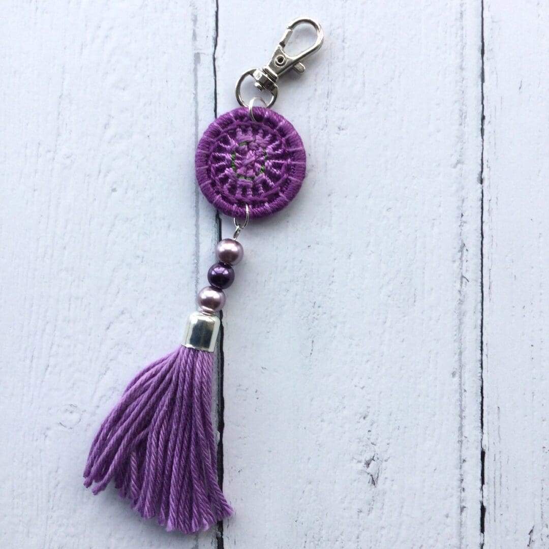 A purple Dorset button and handmade tassel bag charm.