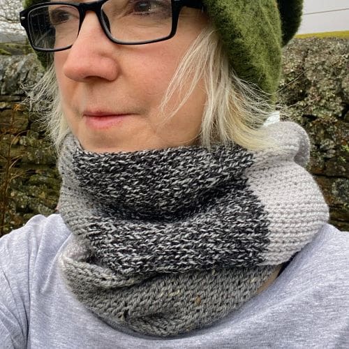 Knitted infinity scarf in shades of textured neutral greys, looped twice around the neck