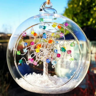 Silver wire tree sitting in an 8cm open fronted glass bauble decorated with a rainbow mix of crystals on the branches with a snowy base.
