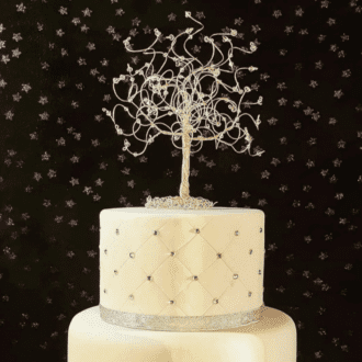 Two tiered wedding cake with a rose gold wire tree cake topper decorated with clear crystals and birthstones on the branches.