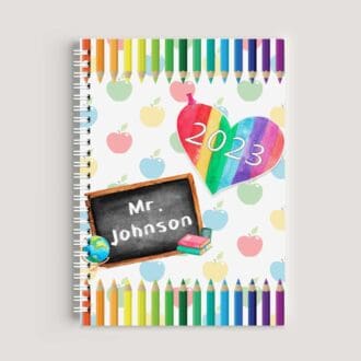 Notebook with pencils and teachers name on blackboard