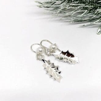 silver holly leaf dangle earrings with freshwater pearl on a white background