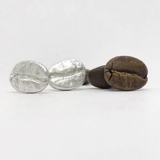 silver coffee bean earrings next to real brown coffee beans on a. white background