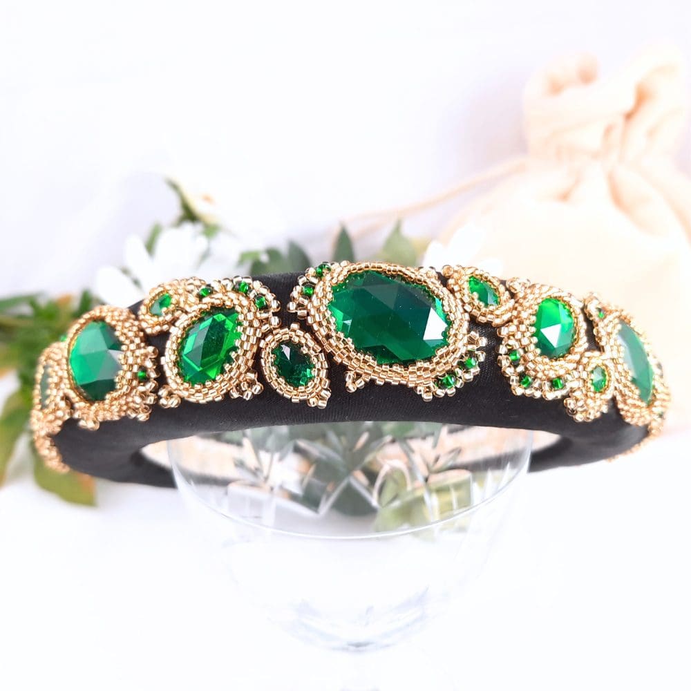 Black padded headbands with green jewels set in gold bezels.