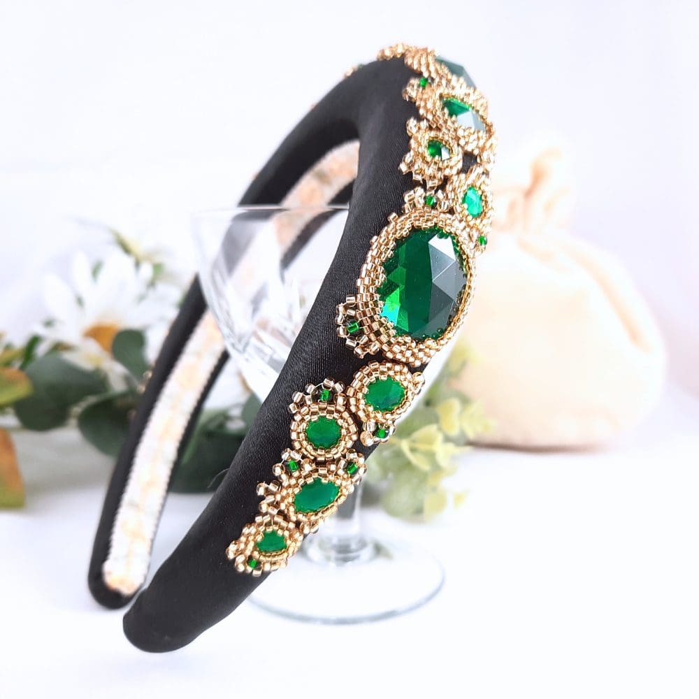 Black padded headbands with green jewels set in gold bezels.