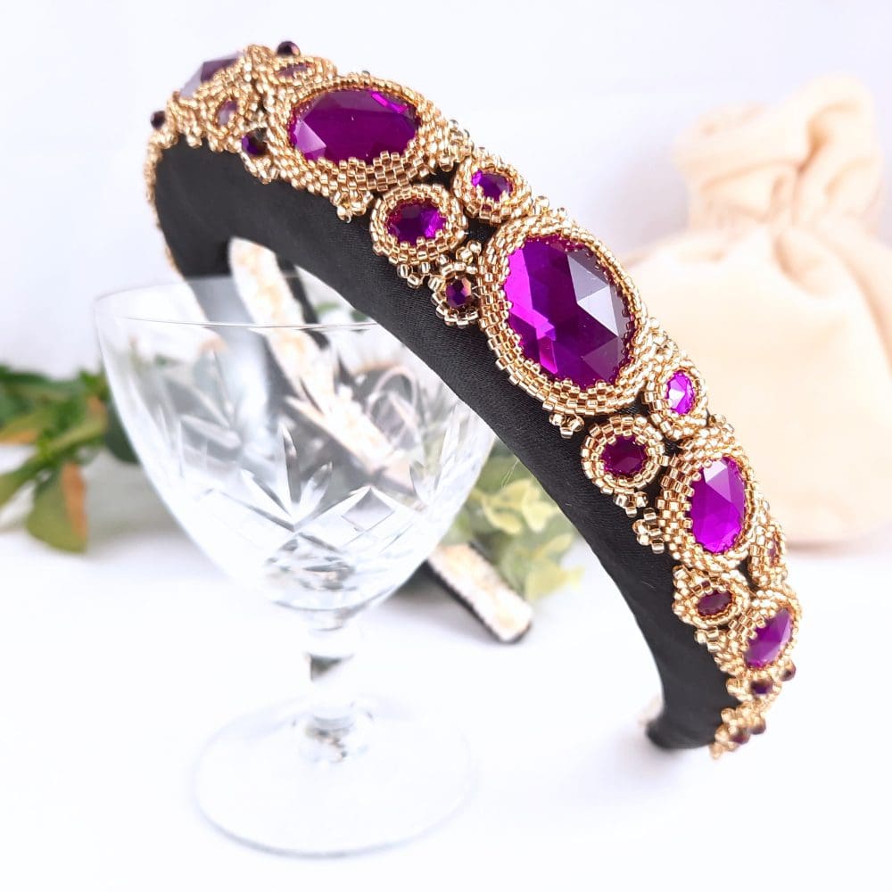 Black padded headbands with purple jewels set in gold bezels.