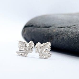 silver sycamore leaf earrings in front of a slate stone on a grey background