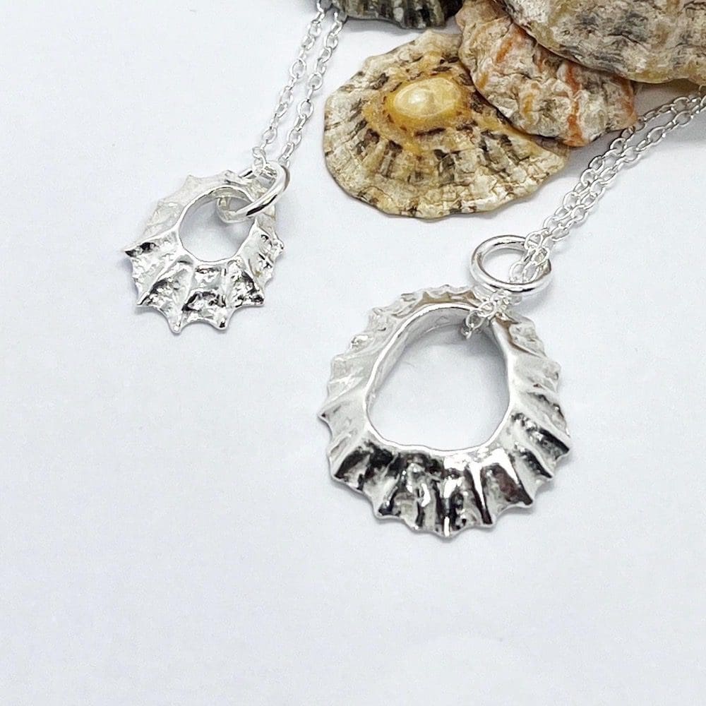 silver limpet shell pendants on a silver chain on a white background