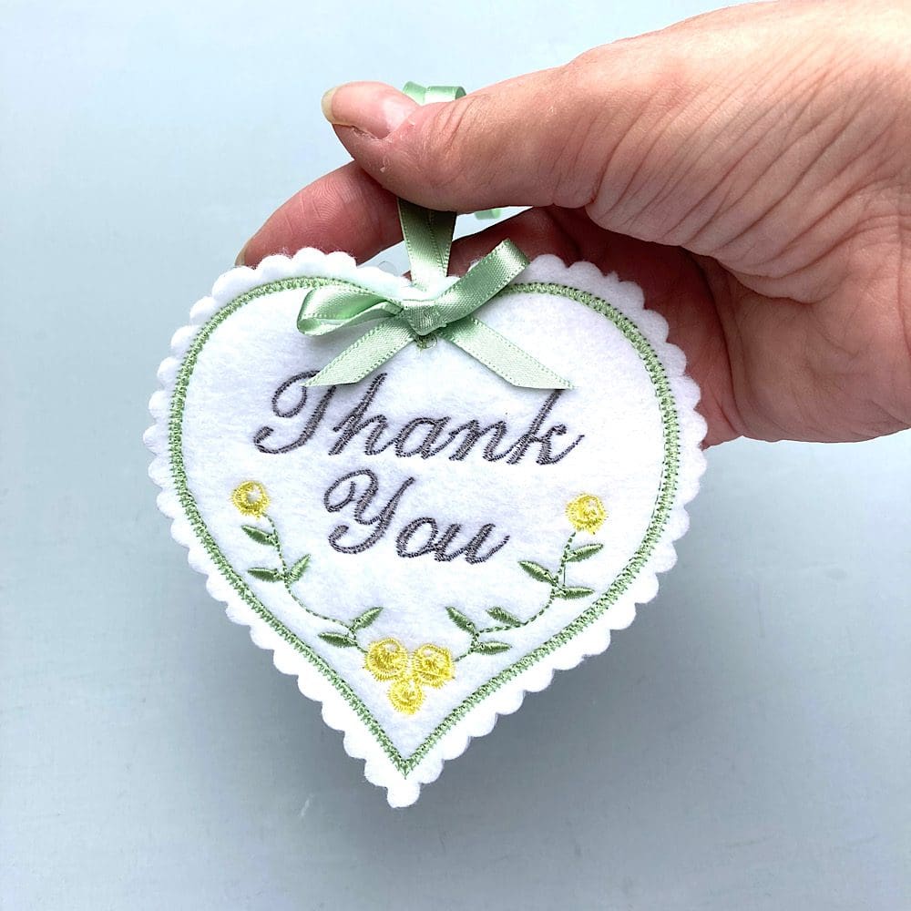 Hand holding embroidered Thank You Heart