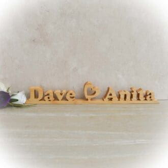Wooden Wedding Table name sign featuring two names with a heart in the middle. The name sign is cut from hardwoods using a scroll saw.