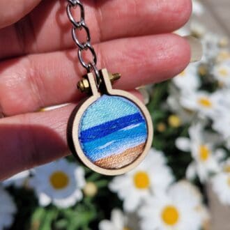 hand embroidered mini hoop keyring with view of the sea. 2.5 cm wooden hoop.