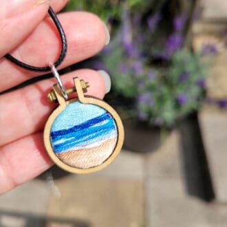 Hand embroidered seascape pendant set in a 2.5 cm mini embroidery hoop frame with choice of leather or silver necklace.