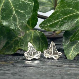 silver ivy leaf earrings surrounded by fresh ivy leaves on a black base