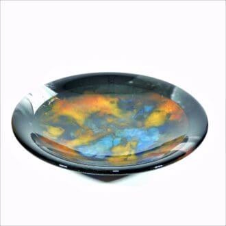 An abstract fused glass bowl with a central swirling pattern made to look like a nebula in space.