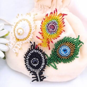 Beaded peacock feather brooches. White, black, natural and rainbow colours.