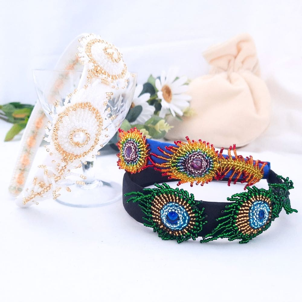 White, natural and rainbow coloured beaded peacock feathers on wide headbands.