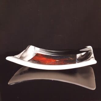 a fused glass dish with a swirl of red and blue colour in the centre made to look like a nebula in space
