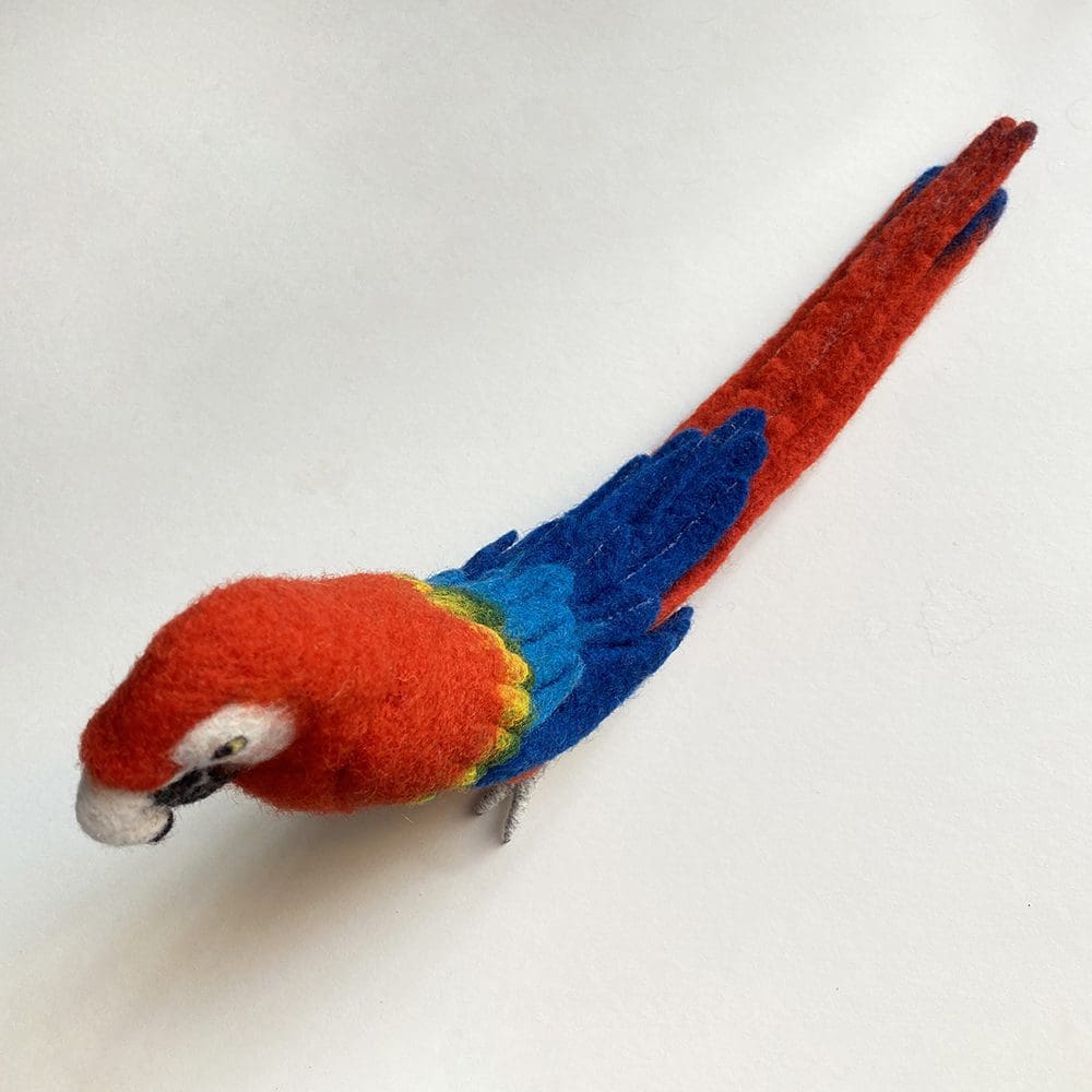 Needle felted sculpture of a red macaw parrot with blue wings, , crafted from colorful wool