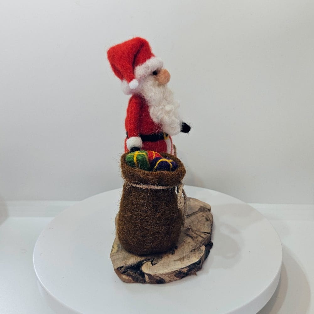 Right side view of needle felted Santa figurine with sack of presents