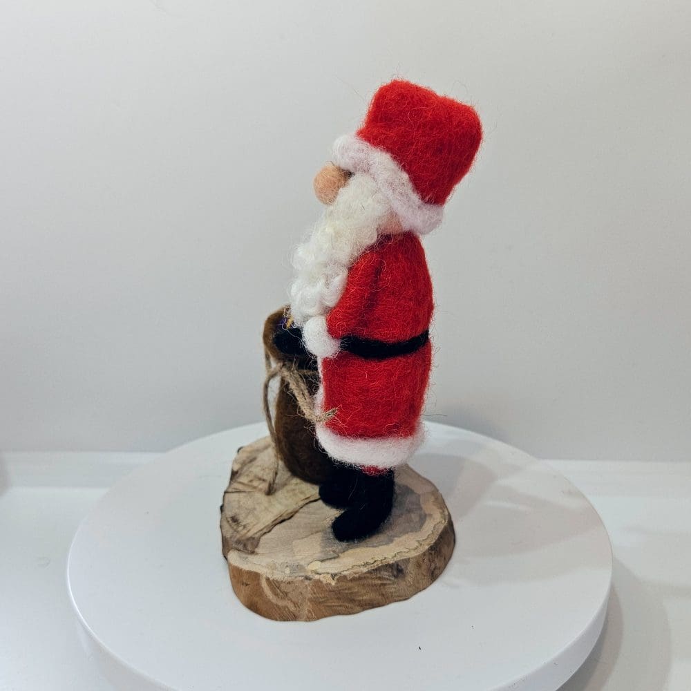 Left side view of needle felted Santa figurine with sack of presents