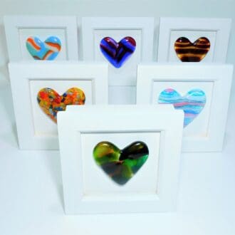A selection of fused glass hearts in various colours mounted in a small box frame