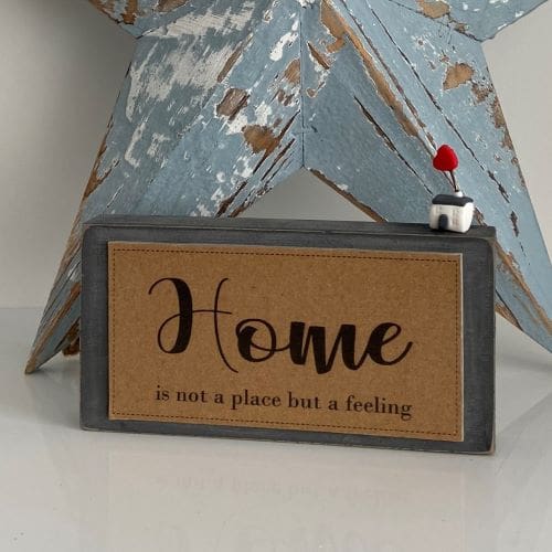 Handmade wooden sign with a miniature clay house - home is not a place but a feeling