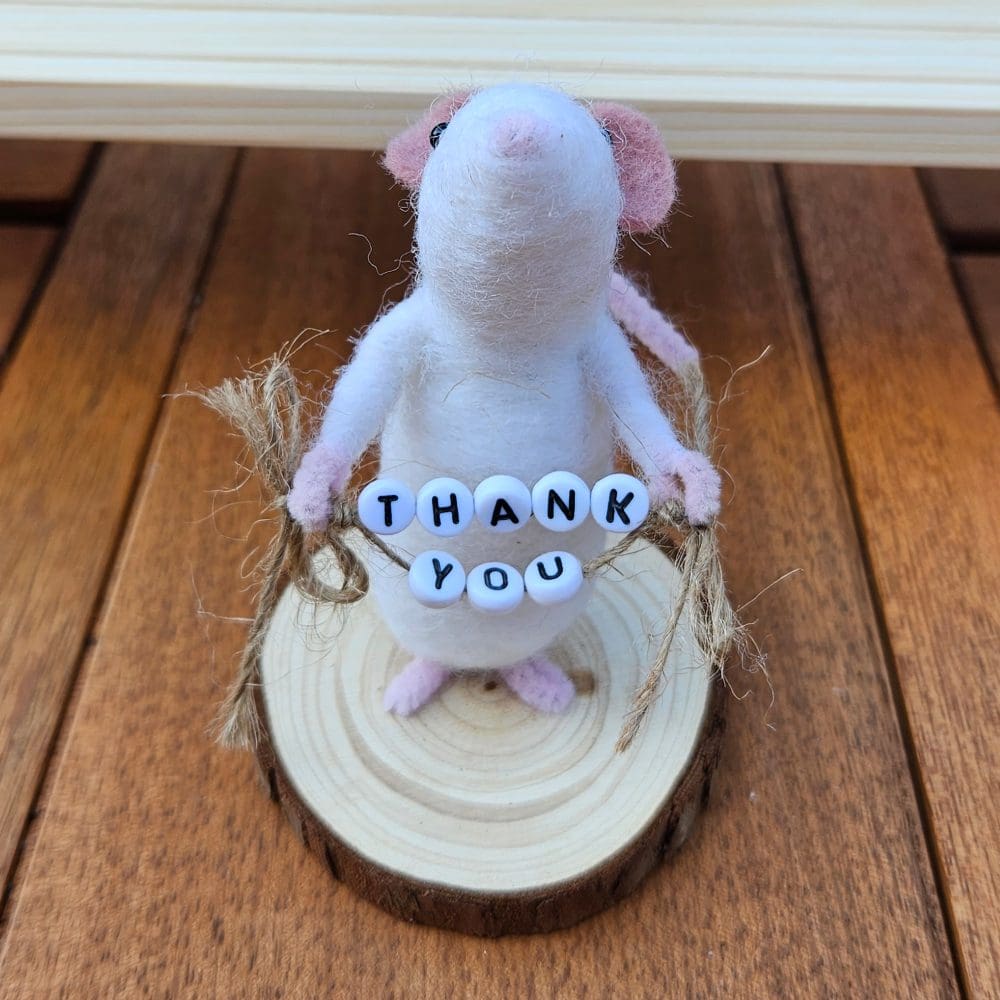 White needle felted mouse holding Thank you bead sign