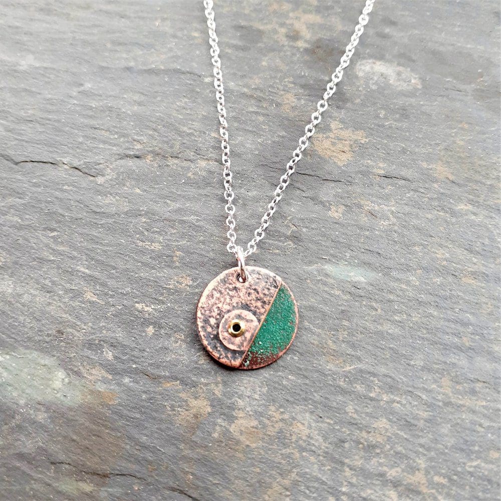 textured copper disc pendant on a silver chain