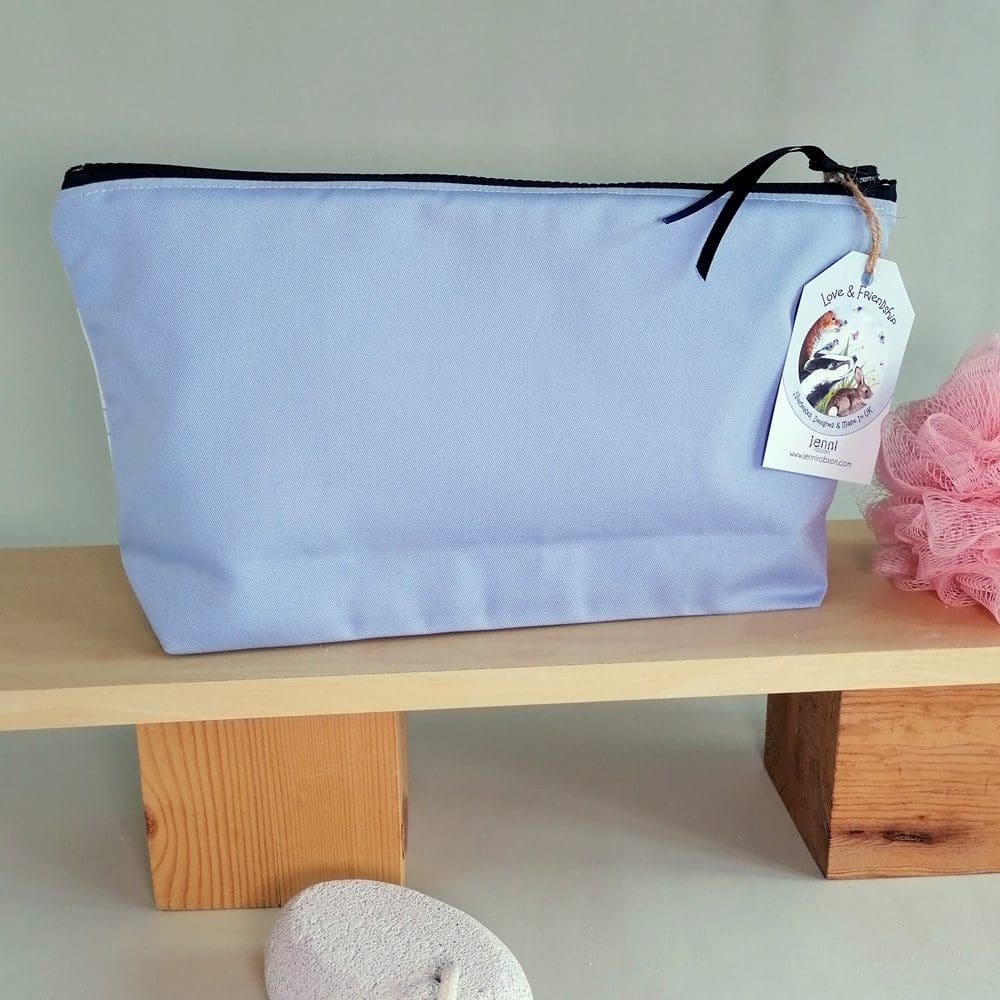 Pale blue back panel of the spotty dog toiletries bag. Made in cotton fabric with a water resistant lining, internal pocket and dark blue chunky zipper fastening.