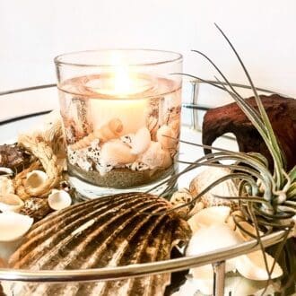 Coast ocean soy gel wax scented candle on a mirror surrounded by shells and air plants