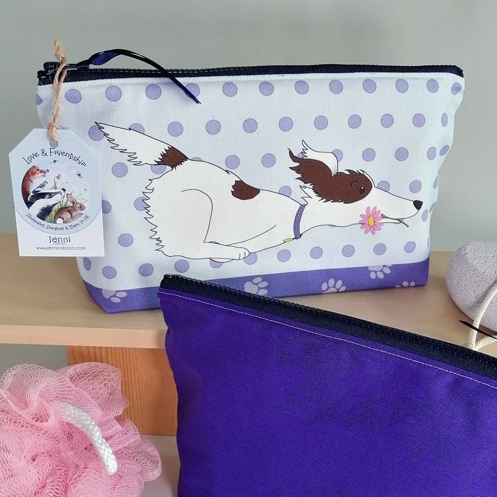 Two toiletries bags displaying the running brown and white dog on a spotty background on one bag and the deep purple back on the second bag.