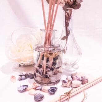 Lavender luxury botanical reed diffuser on a white background surrounded by purple shells and flowers