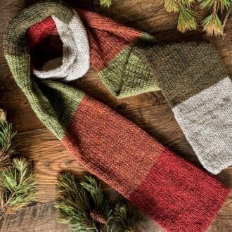 Long knitted scarf with block stripes in rustic shades of woodland greens, browns and reds