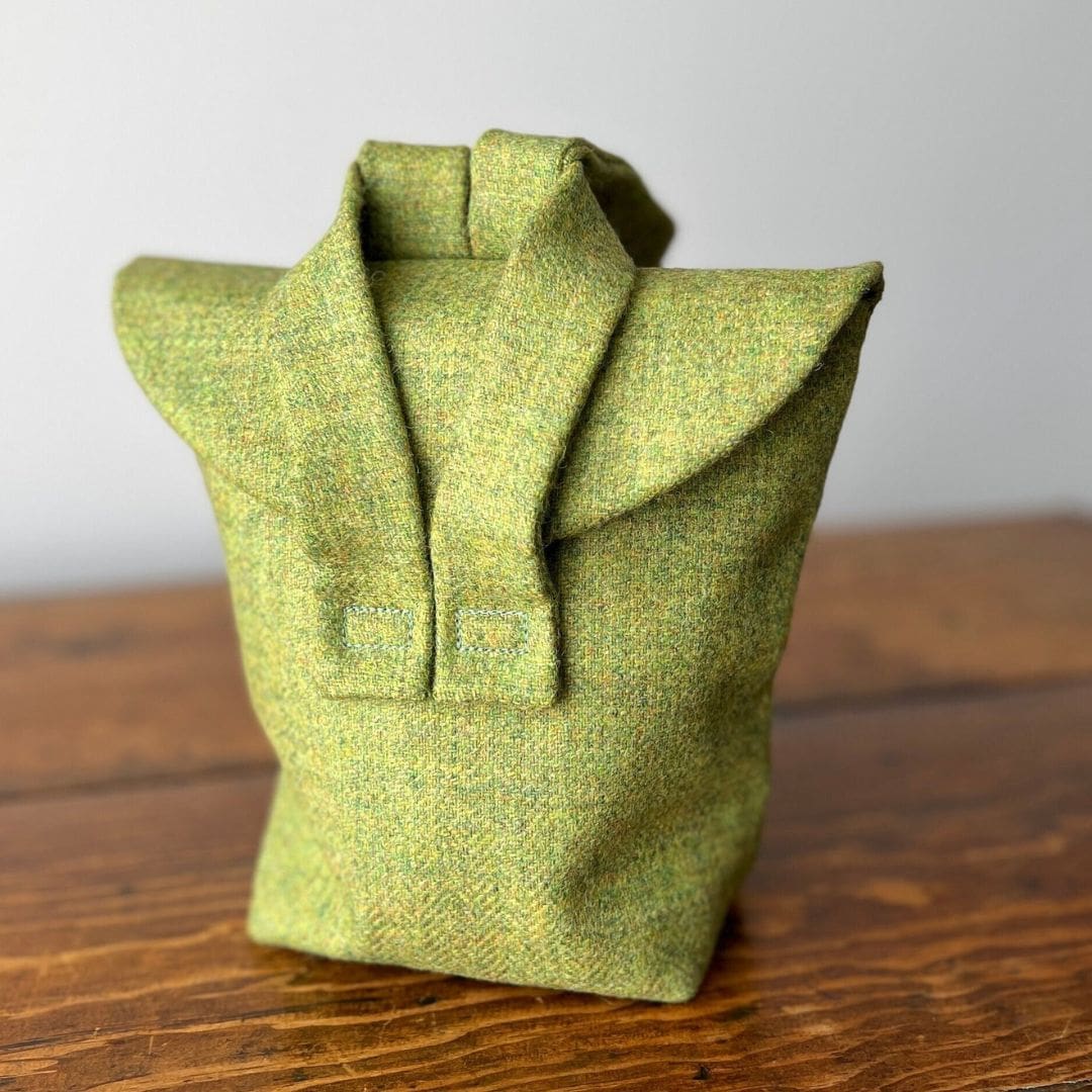 small green bag with cross over straps sitting on a wooden table