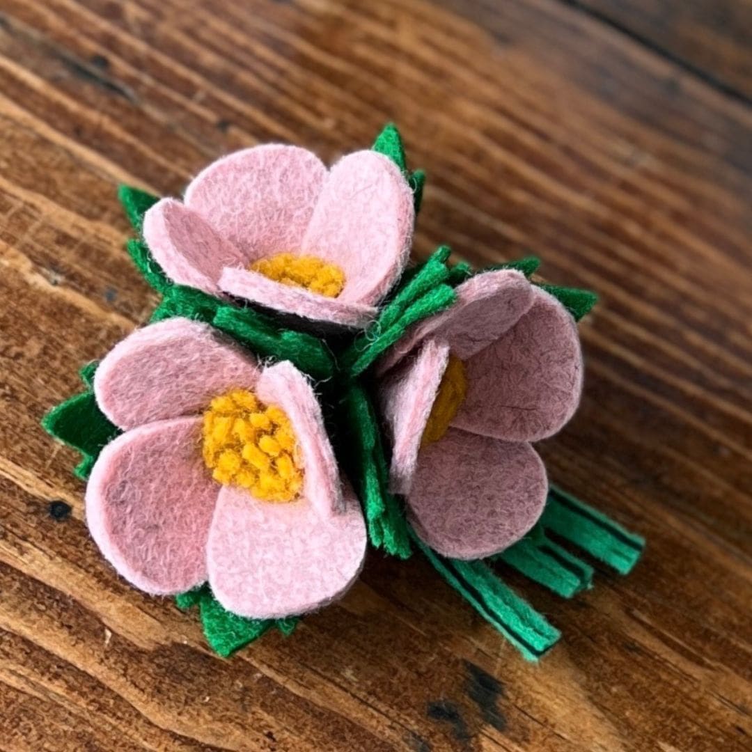 close up photo of the three pale pink flowers of a wool felt brooch