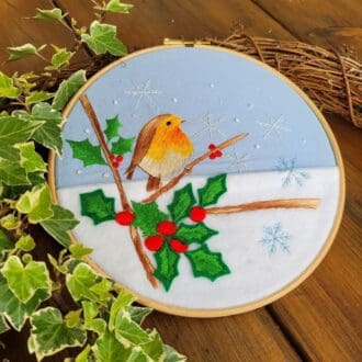 Hand embroidered 8 inch hoop of robin amongst holy Christmas decoration wall hanging.