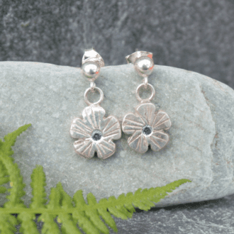 Sterling silver flower earrings with a cubic zirconia stone flush set in the centre.