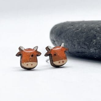 handprinted wooden highland cow earrings on a white background next to a slate stone