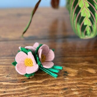 1940s inspired brooch of three pale pink wool felt blooms sitting on a wooden table